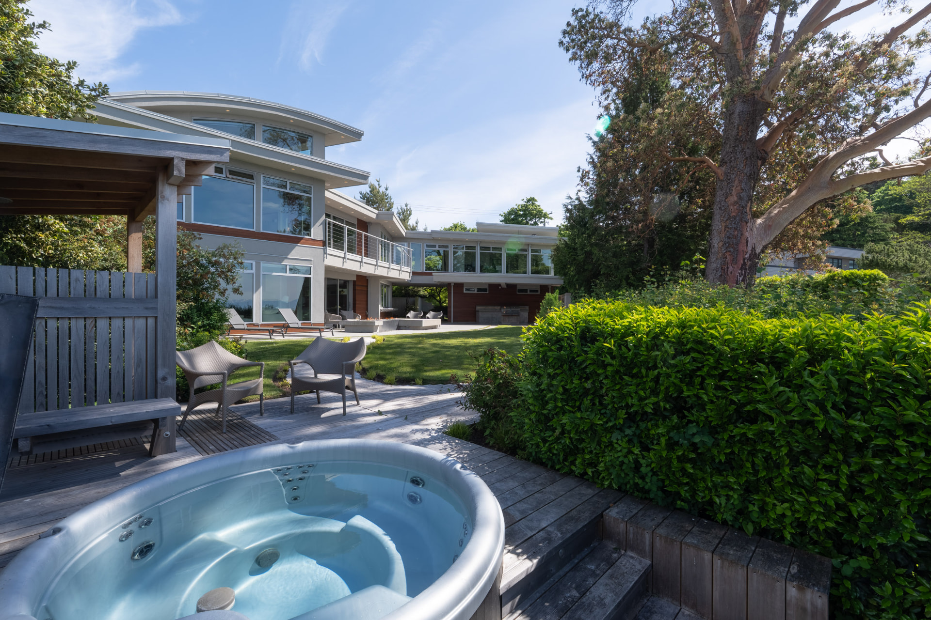 Curved-roof waterfront residence with lawn, hot tub and arbutus tree