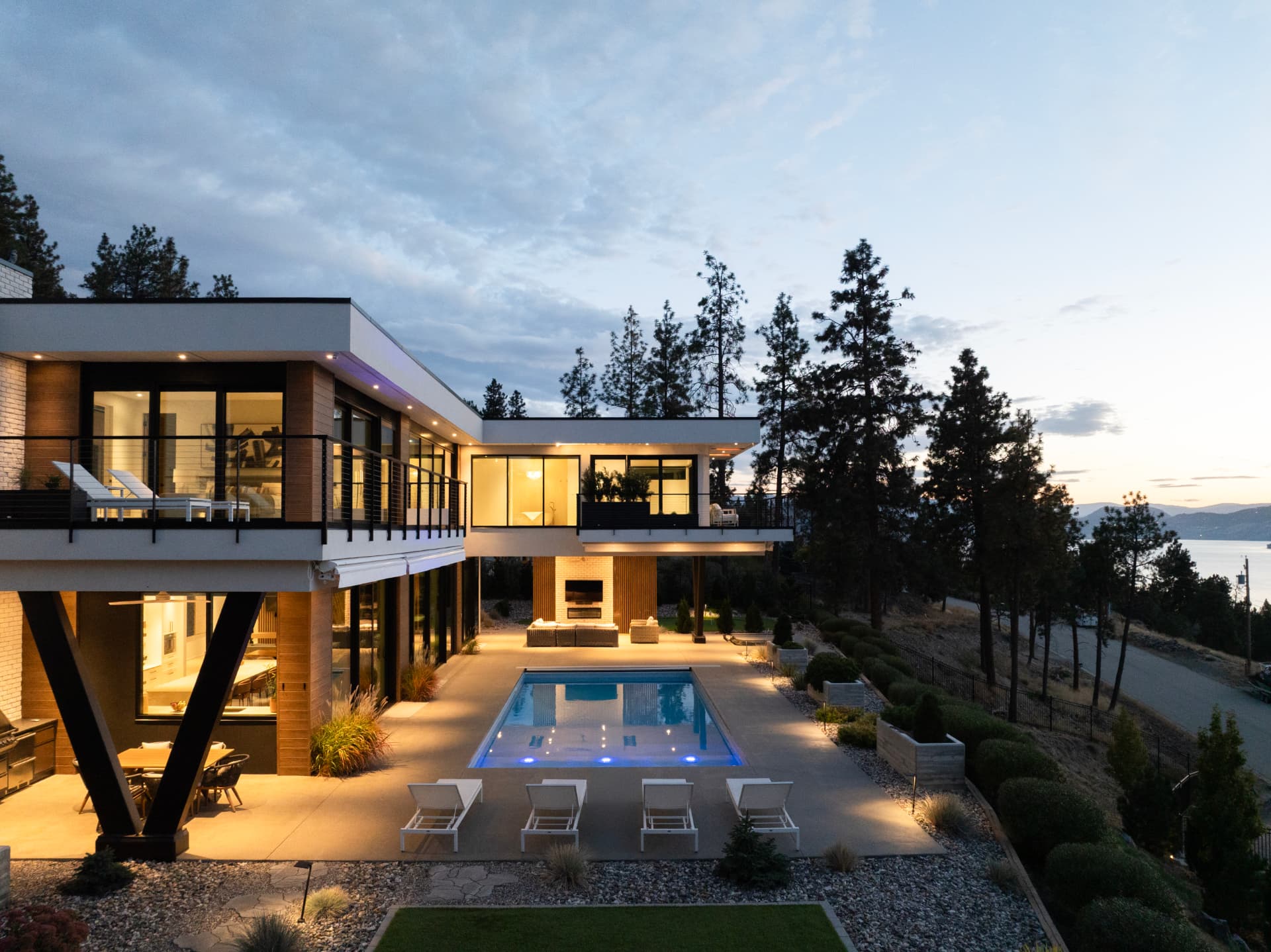 Modern lakeview residence with lit pool and terrace at twilight