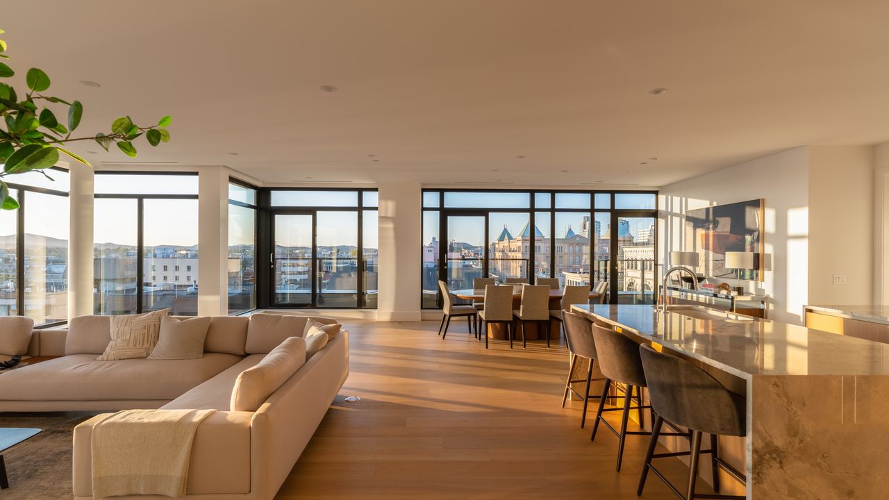 Sunlit open-plan penthouse living and dining room with city views