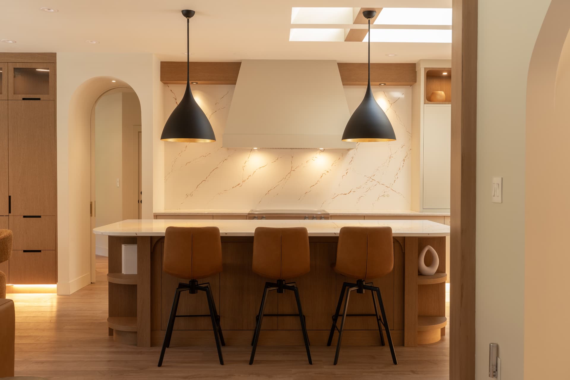 Warm oak kitchen with skylights and black dome pendants